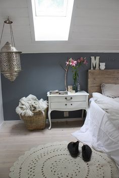 a bedroom with a bed, dresser and window in the corner that has a skylight above it