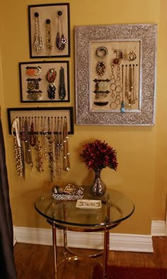 there is a glass table in the room with jewelry on it and pictures hanging on the wall