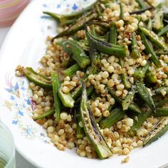 a white plate topped with green beans and couscouse on top of a table