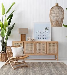 a living room with wicker furniture and plants on the sideboard next to it