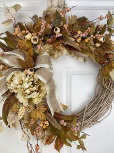 a wreath is hanging on the front door with autumn leaves and berries around it,