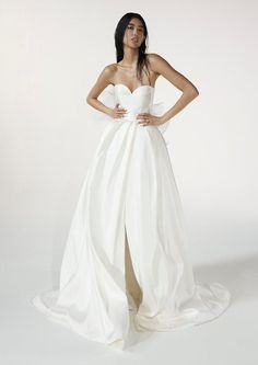 a woman in a white wedding dress posing for a photo with her hands on her hips