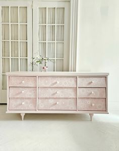 a pink dresser sitting in front of a window