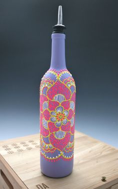 a bottle that is sitting on top of a wooden box and has a flower design painted on it