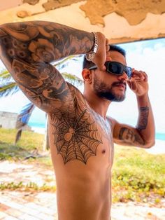 a man with tattoos on his chest and arm is looking at the camera while wearing sunglasses