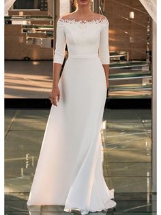 a woman in a long white dress standing on a tile floor with her hand on her hip