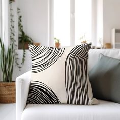 a white couch with two pillows on top of it next to a potted plant