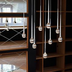 a room filled with lots of glass balls hanging from it's ceiling next to a bookshelf