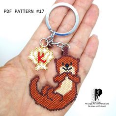 a hand holding a keychain with a fox and maple leaf on it's side