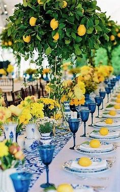 a long table with lemons and blue glassware on it is set for an event