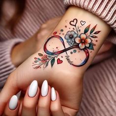 a woman's wrist tattoo with flowers and an infinite sign on the left side