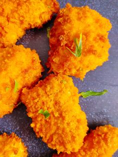 several pieces of fried food are arranged on a plate with green garnishes