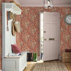 an entryway with floral wallpaper and wooden flooring next to a pink door