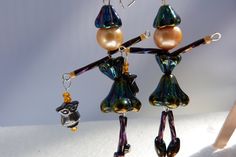 two glass figurines are hanging from earrings