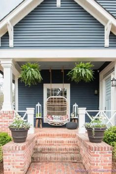 the front porch is decorated with potted plants and hanging birdcage on it