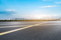 an empty asphalt road with city skyline in the background and blue sky