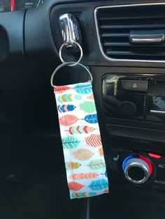 a keychain hanging from the dashboard of a car with an arrow pattern on it