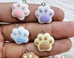 four different colored dog paw charms on someone's hand