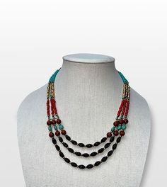 Step into the world of boho chic with our Bohemian Dreams Handcrafted Beaded Multi-Strand Necklace, a perfect blend of free-spirited style and elegance. Features: Intricate Beadwork: Black, red, turquoise, and golden beads are thoughtfully arranged to create a vibrant, captivating design. Adjustable Length: The necklace features an adjustable hook clasp, allowing you to customize the length for any outfit or occasion. Versatile Style: Ideal for both casual and formal wear, this statement piece complements a wide range of looks. Artisan Craftsmanship: Handcrafted by skilled artisans, each necklace is a testament to their dedication and attention to detail. Size & Material: Material: High-quality beads with a sturdy link chain Style: Multi-strand, adjustable length Care Instructions: Store i Bohemian Multi-strand Black Bead Jewelry, Bohemian Black Multi-strand Beads, Bohemian Oval Bead Jewelry For Festivals, Artisan Beaded Necklace With Gemstone Beads For Beach, Bohemian Black Beads Jewelry, Bohemian Festival Necklaces With Oval Beads, Bohemian Necklace With Oval Beads, Bohemian Oval Beads With Beaded Chain, Bohemian Oval Beads Necklace For Festival