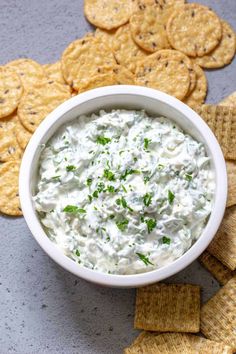 a white bowl filled with dip surrounded by crackers