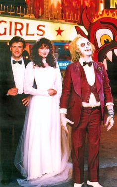 a man and woman dressed up as the bride and groom in front of a circus sign