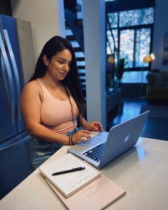 a woman sitting at a table using a laptop computer