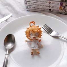 an action figure sitting on top of a white plate next to a fork and knife