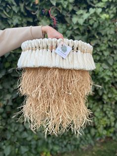 a person holding a piece of straw in front of a bushy area with green plants