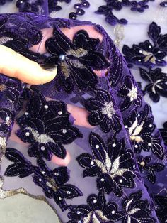 Stunning lace to make every woman look beautiful and stand out. Purple velvet roses and sequins on black mesh tulle. Width is 135 - 140 cm price unit is one yard All orders over one yard will be in a continuous length. Matching purple stretch crepe back satin available in our shop.