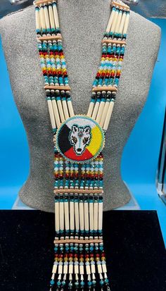 Bone hairpipes and crystal beads are often seen as part of traditional Native American dancers.  This modified breastplate  has been created to proudly proclaim that this is a good day to be Indigenous . It is designed to be worn not only in the dance circle, but in mainstream life, showing your Native pride and fashion sense.   The necklace is 10 vertical strands of bone hairpipes, nickel beads and 8mm sparking, faceted, fire-polished glass crystal beads in the colors of Snow White, emerald green, pale green, lilac and amethyst purple.  The centerpiece is a beaded rosette of a Wolf with golden eyes and a genuine turquoise cabochon on her forehead. She is surrounded by the colors of the Four Directions and lined with turquoise beads of the sky. The breastplate is done with sparkling facete The Four Directions, Native Regalia, Chest Plate, Native Pride, Four Directions, Golden Eyes, Wolf Spirit, Native American Fashion, Bone Beads