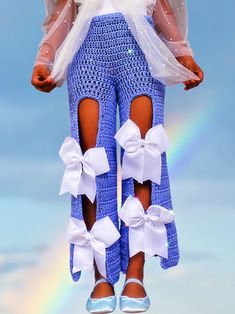 a doll dressed in blue and white is standing on a rainbow background