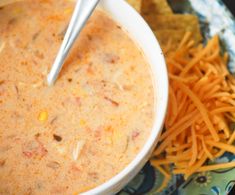 a white bowl filled with soup next to cheese and crackers on a blue plate