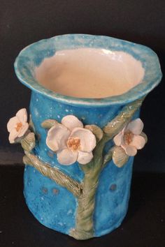 a blue vase with flowers painted on the outside and in the inside, sitting on a black surface