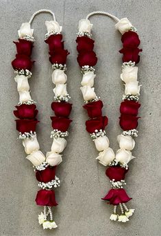 two red and white roses are attached to a string with pearls, beads and flowers