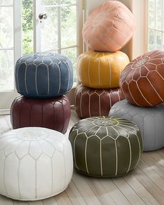 several different colored poufles stacked on top of each other in front of a window