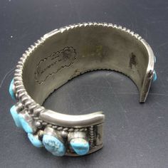 "VINTAGE NAVAJO BRACELET DESCRIPTION: This impressive cuff features 21 specimens of blue Arizona turquoise.. The gemstones are secure in smooth bezel, on a foundation of heavy gauge vintage sterling silver. Plump applied raindrops punctuate the turquoise cabochons and chisel stamped designs frame the edges. This fine bracelet will be a cherished addition to your collection of fine vintage Native American jewelry. MEASUREMENTS: Interior of the cuff measures 5 7/8\" with an additional 1 1/4\" non- Vintage Blue Bangle Bracelets, Vintage Stamped Blue Jewelry, Blue Vintage Stamped Jewelry, Vintage Blue Cuff Bracelet, Vintage Turquoise Cuff Bracelet, Handmade Vintage Cuff Bangle, Vintage Blue Cuff Jewelry, Vintage Cuff Bracelets For Collectors, Vintage Cuff Bracelets Collectible