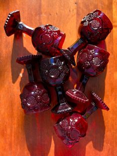 a bunch of red glass objects sitting on top of a wooden table