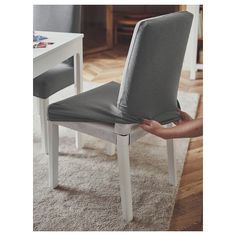 a person holding up a chair cushion in front of a dining room table and chairs