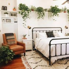 a bed room with a neatly made bed next to a chair and potted plants