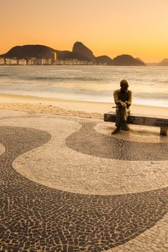 a man sitting on top of a bench next to the ocean