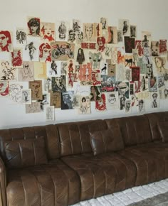 a brown leather couch sitting in front of a wall with pictures on the wall behind it