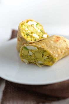 two burritos on a white plate with a brown napkin