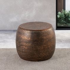 a large round stool sitting on top of a carpeted floor next to a window