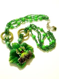 a necklace with green beads and a flower on the front is laying on a white surface