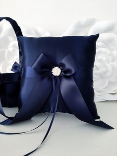 a blue pillow with a bow on the side and ribbon tied around it, sitting in front of a white wall