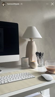 a desktop computer sitting on top of a desk next to a lamp and glass vase