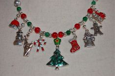 I hand beaded this one-of-a kind Holiday necklace with enamel and silver tone metallic Christmas charms and glass and silver tone beads.  The center charm pendant is an enamel and silver Christmas tree topped with a lampworked glass star bead. The other eight charms are a Santa hat, a snowman, a reindeer, candy canes, a Christmas stocking, an old-time Santa, a gingerbread man, and Santa's sleigh.  Happy Holidays This necklace has a J-hook clasp and is lightweight and comfortable to wear. Ours is a non-smoking home. Christmas Jewelry Gift With Dangling Beads, Christmas Gift Jewelry With Dangling Beads, Beaded Jewelry For Christmas Celebrations, Gift Silver Beads Dangle Necklaces, Silver Beads Dangle Beaded Necklaces As Gift, Silver Holiday Necklaces For Festive Occasion, Nickel-free Silver Necklaces For Christmas, Nickel-free Silver Necklace For Christmas, Silver Holiday Necklace For Festive Occasion