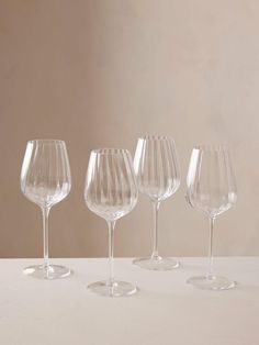 four clear wine glasses lined up on a table