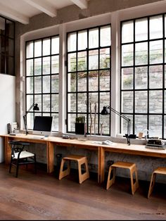 an office with three desks and two chairs in front of large windows that look out onto the street