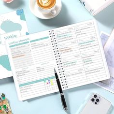 an open planner sitting on top of a blue table next to a cup of coffee